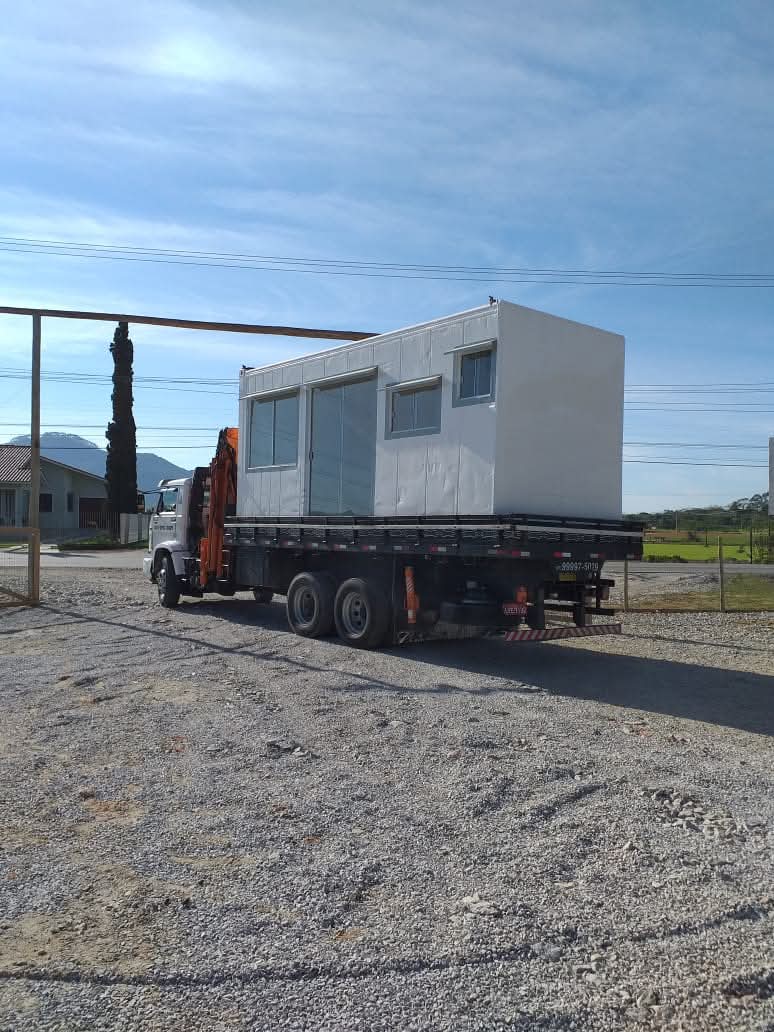 Mini casa branca chegando ao destino sobre caminhão